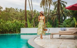 a woman standing next to a pool at a resort at Lamrin Morjim Goa in Morjim