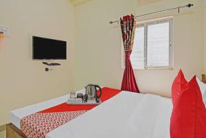 a bedroom with a bed with a red blanket and a television at Sapphire Guest House in Kolkata
