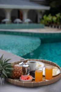 a tray of juice and fruit on a table next to a pool at Lamrin Morjim Goa in Morjim