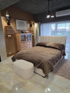 Un dormitorio con una cama grande y una otomana blanca. en Vinetas Apartments Nr3 The One, en Cēsis