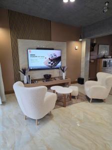 sala de estar con sillas blancas y TV de pantalla plana en Vinetas Apartments Nr3 The One, en Cēsis