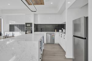 une cuisine blanche avec des comptoirs et des appareils blancs dans l'établissement Modern Family Home Near Kallo Town Centre, à Kalkallo