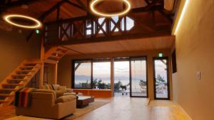 a living room with a staircase and a living room with windows at 夕日ヶ浦温泉 天然温泉 茜海旅館 in Kyotango