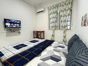 a bedroom with a bed and a flat screen tv at Dehome Suko Syariah in Surabaya