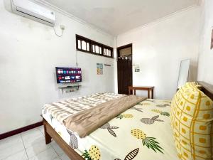 a bedroom with a bed and a flat screen tv at Dehome Suko Syariah in Surabaya