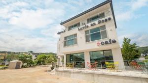 un bâtiment avec des tables et des chaises devant lui dans l'établissement Gyeongju La Vie en Rose, à Tongnyŏng
