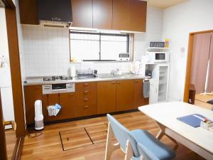 a kitchen with wooden cabinets and a table and a table and chairs at Bhome Hikone Jizo in Hikone