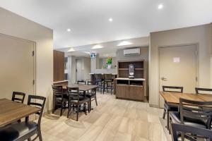 a dining room with tables and chairs and a kitchen at Quality Inn Centre-Ville in Montréal