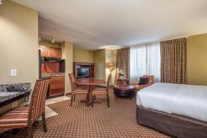 a hotel room with a bedroom with a bed and a table at Clarion Collection Hotel Arlington Court Suites in Arlington +63 photos