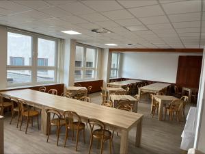 una grande stanza con tavoli, sedie e finestre di Sportcentrum Brandýs a Brandýs nad Labem-Stará Boleslav