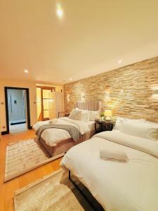 a bedroom with three beds and a brick wall at Tower Bridge Apartments in London