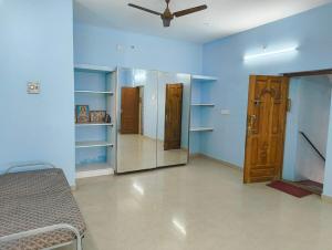 a room with blue walls and a bed and a ceiling fan at KHS Keshav-U in Ambāsamudram