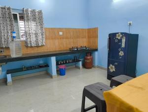 a kitchen with a blue wall and a refrigerator at KHS Keshav-U in Ambāsamudram +5 photos