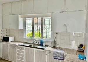 a kitchen with white cabinets and a sink and a window at Budget-Friendly Chermside Home Near Westfield in Brisbane