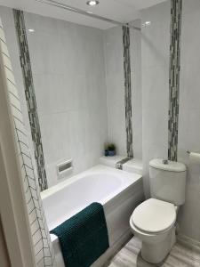 a white bathroom with a tub and a toilet at Penarth Station Renovated apartment in Cardiff