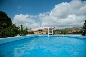 a blue swimming pool with a white umbrella at Casavacanza Dattilo in Dattilo