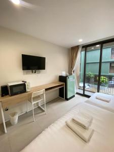 a bedroom with a bed and a tv and a desk at POP Heritage Residence in Bangkok