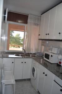 a kitchen with white cabinets and a sink and a microwave at Precioso ático a pie de playa, en Miño in Miño