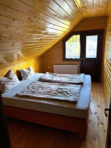Una cama grande en una habitación con techo de madera. en Szakács Vendégház, en Borzont