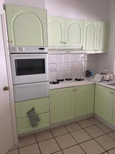 a kitchen with green cabinets and white appliances at Double room with shared bathoom in Auburn +15 photos