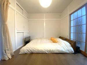 un orsacchiotto seduto su un letto in una camera da letto di e101 阿佐ヶ谷ローズハウス a Tokyo
