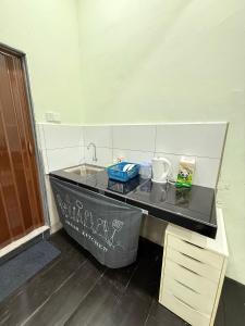 a kitchen with a black counter with a sink at cozy nest panji in Kota Bharu +4 photos