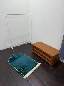 a rug on the floor next to a wooden table at cozy nest panji in Kota Bharu