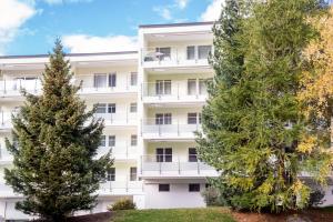 an apartment building with two trees in front of it at Alpine Lodge 63 in Andermatt