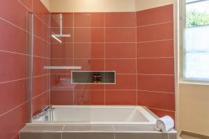 a bath tub in a bathroom with red tiles at La Bastide - 8 personnes - Maison avec jardin in Lescar +34 photos