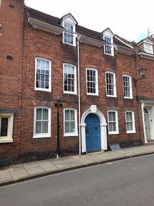 un edificio de ladrillo con una puerta azul en una calle en St Johns Hill Apartments, en Shrewsbury