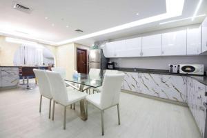 Un comedor con una mesa de cristal y sillas blancas. en Wecation - 5BR Villa With Private Swimming Pool, en Dubái