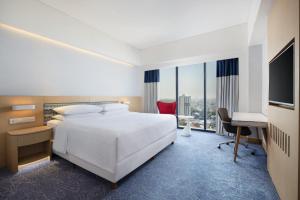 a hotel room with a bed and a desk and a television at Four Points by Sheraton Surabaya, Tunjungan Plaza in Surabaya +35 photos