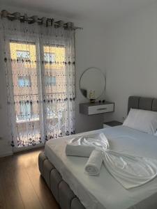 a bedroom with a white bed with a mirror at Mme apartment in Kamëz