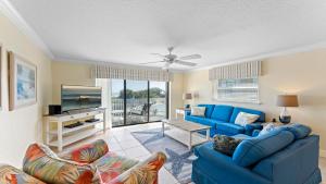 Una sala de estar con un sofá azul y un televisor. en Ola Grande by Happy Palm Stays, en Cocoa Beach