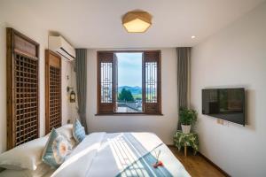 a bedroom with a large bed and a window at Wuyuan Jiwei Mountain Lodge (Sixi-Yan Village Scenic Area) in Wuyuan