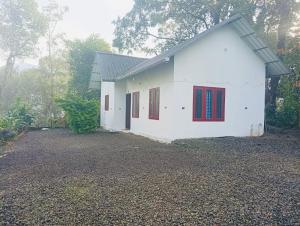 a white house with red doors and a gravel yard at Munnar Hills And Mist Views in Anachal +21 photos