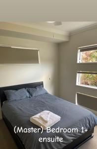 a bedroom with a bed and two windows at Spring Mountain Family Stay in Ipswich