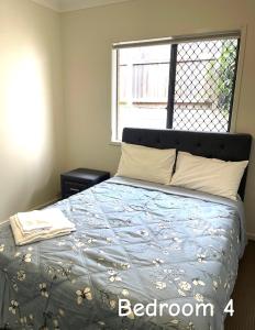 a bedroom with a bed with a blue comforter and a window at Spring Mountain Family Stay in Ipswich