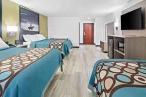 a hotel room with two beds and a flat screen tv at Super 8 by Wyndham Weatherford in Weatherford