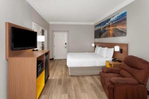 アーリントンハイツにあるDays Inn & Suites by Wyndham Arlington Heightsのベッドと薄型テレビがあるホテルの部屋
