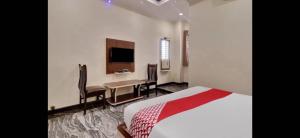 BidadiにあるHotel O Bidadi Railway Junction Bangalore Formerly Ejallaのベッドとテーブルとテレビのある寝室