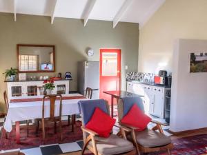 una cocina con mesa y sillas con almohadas rojas en Bella Rosa Cottage, en Clarens