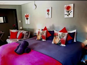 1 dormitorio con 1 cama grande con almohadas moradas y rojas en Bella Rosa Cottage, en Clarens