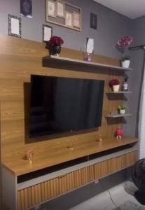 TV de pantalla plana en un centro de entretenimiento de madera en Casa temporada Tarumã 02, en Tangará da Serra