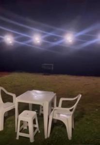 Una mesa blanca y dos sillas y un aro de baloncesto. en Casa temporada Tarumã 02, en Tangará da Serra