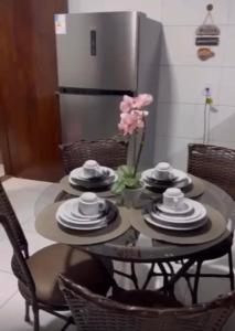 una mesa con platos y un jarrón de flores. en Casa temporada Tarumã 02, en Tangará da Serra