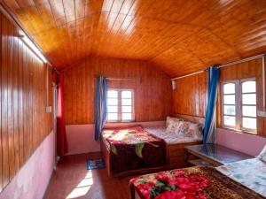a bedroom with two beds in a wooden room at Peshok Subba Homestay By StayApart in Darjeeling +7 photos