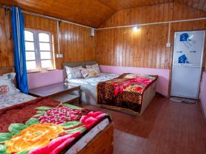 a small room with two beds and a refrigerator at Peshok Subba Homestay By StayApart in Darjeeling