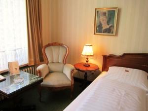 ハンブルクにあるホテル ステファンのベッド、椅子、テーブルが備わるホテルルームです。