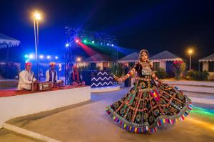a woman in a colorful dress dancing at a wedding at The Saffron Desert Camp, Jaisalmer in Jaisalmer